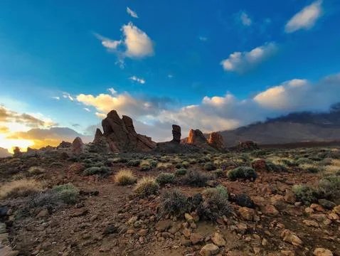 Rock formations under a cloudy sky at sunset in a mountainous area Stock Photos