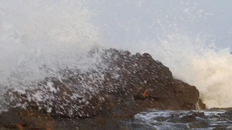 A rock in front of the coast is overrun by a wave with a lot of spray. Stock Footage 138207535