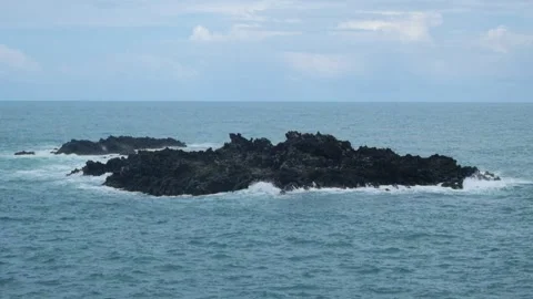 A rock in the middle of the sea hit by waves Stock Footage 319844984