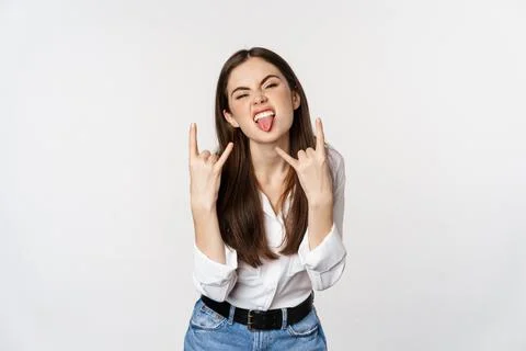 Rock n roll. Young woman showing rock on, heavy metal sign, having fun, standing Stock Photos