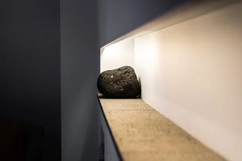 Rock resting on a smooth surface illuminated by warm light in a modern interior Stock Photos