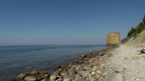 Rock "Sail" on shore of stone beach. Sea is calm. Tourists go to side of rock. Stock Footage 134062539