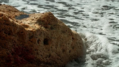A rock in the surf line that is flooded by the waves. Long shot taken with a Stock Footage 220633139