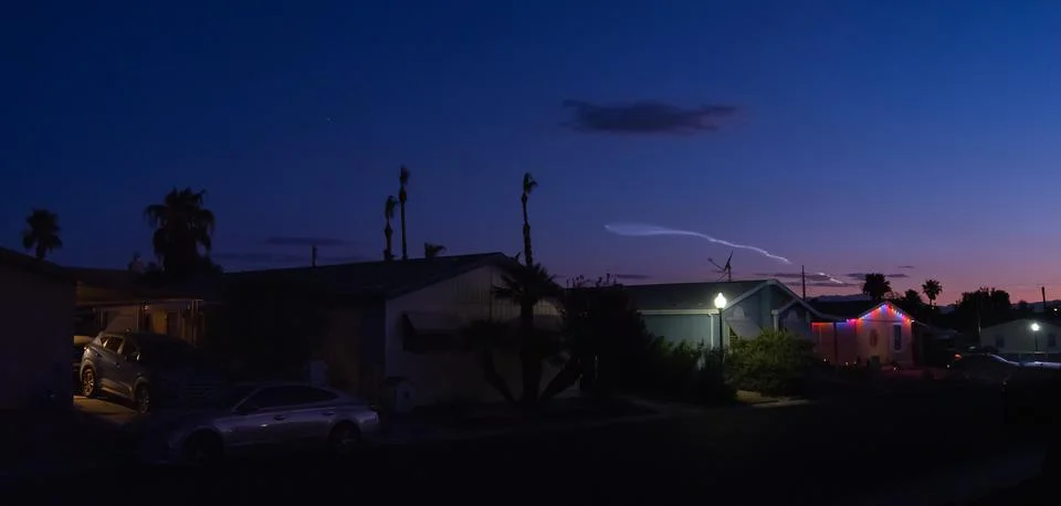 Rocket launch ascends the twilight sky over a colorful neighborhood community. Stock Photos