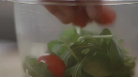 Rocket leaves and cherry tomatoes being put into plastic container Stock Footage 194477741