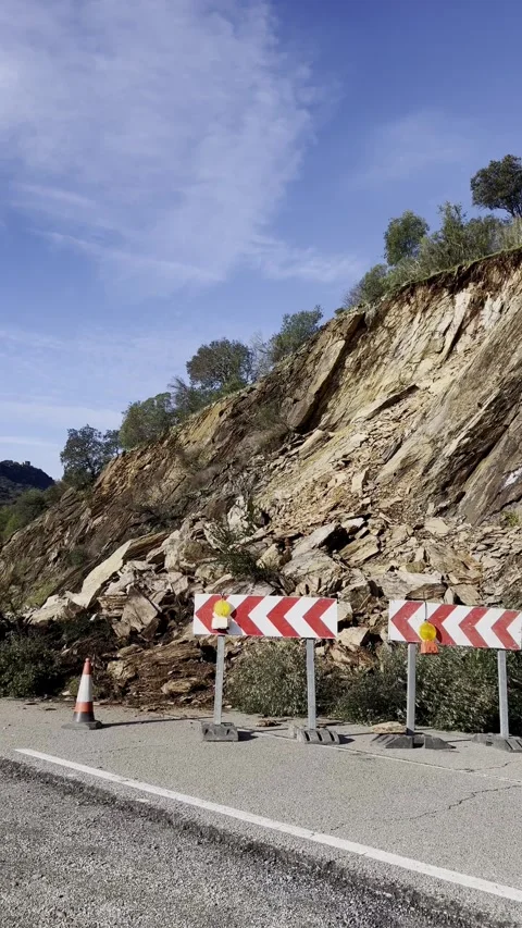 Rockfall blocking mountain road with warning barriers Stock Footage 328973222