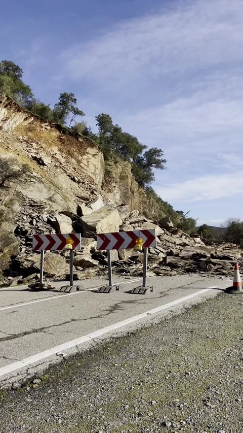 Rockfall blocking mountain road with warning barriers Stock Footage 328973226