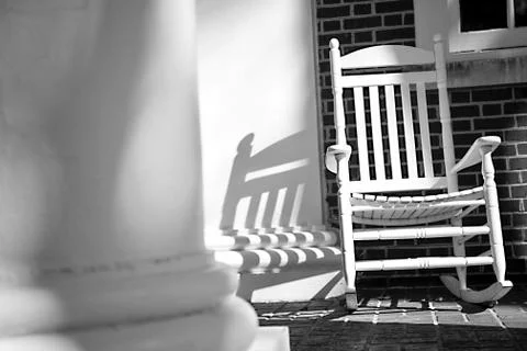 Rocking chair on dramatic empty front porch Stock Photos