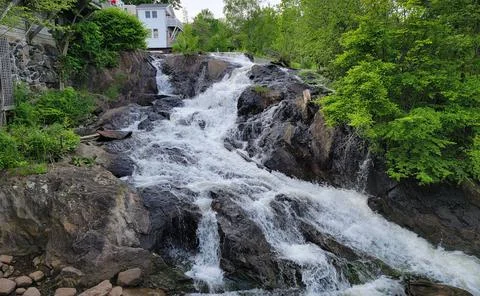 Rocks and waterfall or cascade with trees and buildings Stock Photos