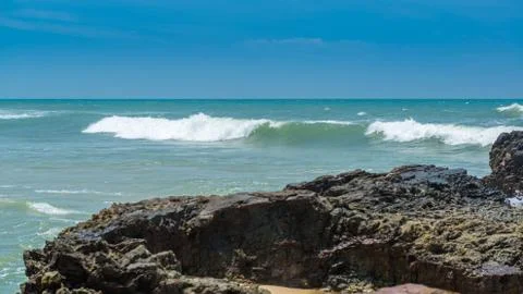Rocks by the beach with waves splahes Stock Photos