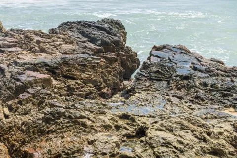 Rocks by the beach with waves splahes Stock Photos