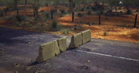 Rocks blocking a remote dirt road in arid landscape during daylight hours Stock Illustration