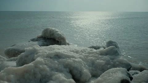 Rocks covered with ice on beach of tranquil shiny ocean Stock Footage 151140698