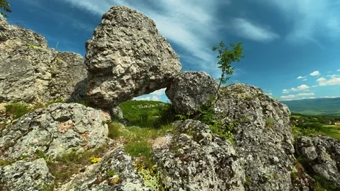 Rocks form natural arch over vibrant green grass. Vrmdza Fortress. Serbia Stock Footage 338021470