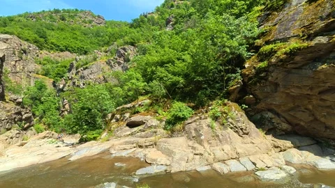 Rocks frame a rushing stream beneath clear blue skies. Vucjanka Canyon, Serbia Stock Footage 341127493