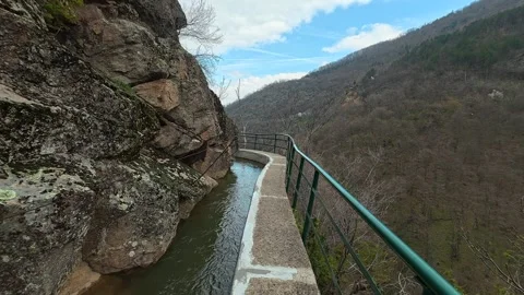 Rocks line a narrow stream beside a paved path. Vucjanka Canyon, Serbia Vidéo 332170546