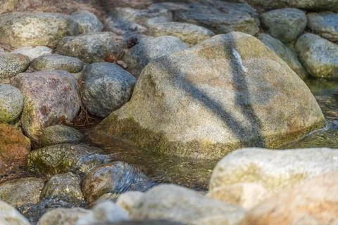 Rocks line a shallow stream, smooth from water's flow 写真素材