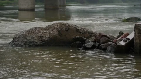 Rocks lying in flowing river water bridge pillar behind in water Stock Footage 225740519