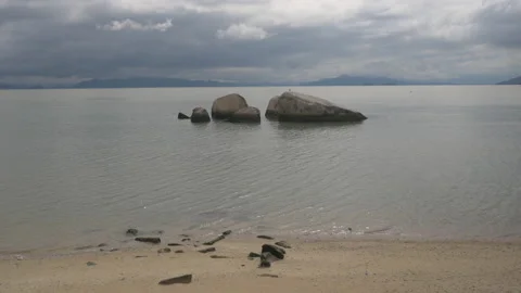 Rocks in the middle of a lake by the beach on a cloudy day, in Brazil Stock Footage 231547980