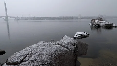 Rocks over the water of a quiet river on a snowy overcast day Stock Footage 100690977