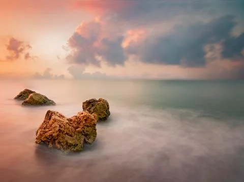 Rocks in sea over dramatic sky during sunrise Foto stock