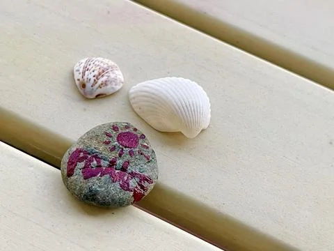 Rocks, shells, and a rose pattern painted on a piece of wood Stock Photos