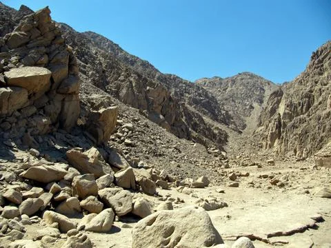 Rocks in the Sinai mountains. Gorge of gray-yellow stones against the blue sk Stock Photos