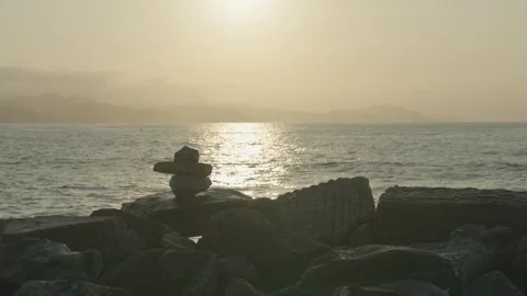 Rocks stacked in front of the sea with the sun in the background Stock Footage 297791698