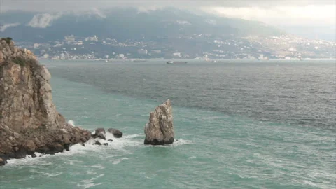 Rocks in the waves against the background of the city Video stock 134487955