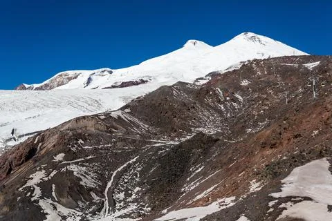 Rocks, white slopes and the summit of Elbrus, Caucasus Stock Photos