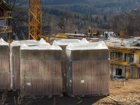 Rockwool insulation stacks at an active construction site with workers on a Stock Photos