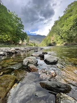 Rocky area on the shore of a river between mountains. Stock Photos