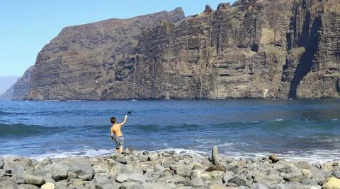 Rocky beach below the towering cliffs of Los Gigantes with a boy throwing stones Stock Photos