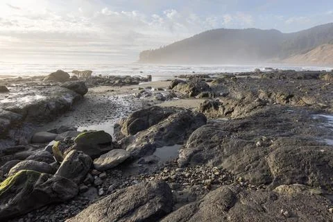 A rocky beach with a cloudy sky in the background Stock Photos
