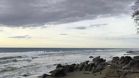 Rocky beach landscape: Ocean waves crashing on rocky shore under cloudy sky. Stock Footage 344161980