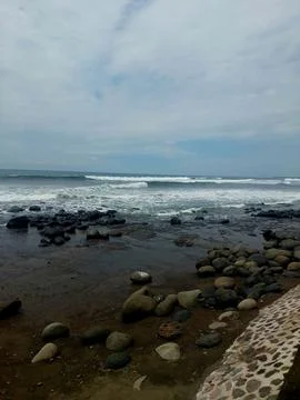 Rocky Beach with Ocean Waves Under Cloudy Sky. Stock Photos