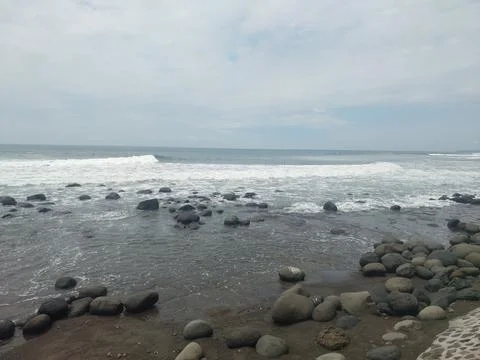 Rocky Beach with Ocean Waves Under Cloudy Sky. Stock Photos