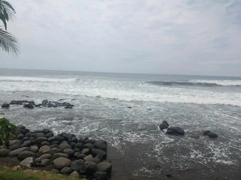 Rocky Beach with Ocean Waves Under Cloudy Sky. Stock Photos