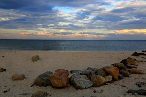 Rocky beach shoreline with dramatic clouds over the ocean at dusk Stock Photos