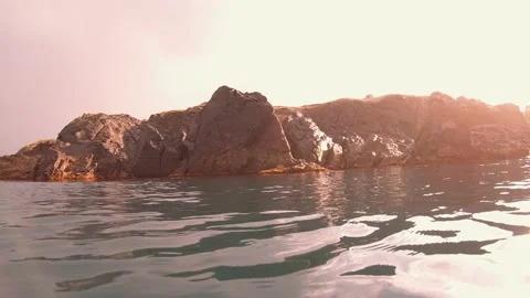 Rocky beach with sun and clouds Stock Footage 133023318