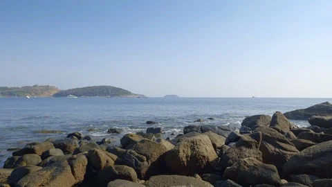 Rocky beach with waves and splashes and islands with hills and boats Video stock 114983611