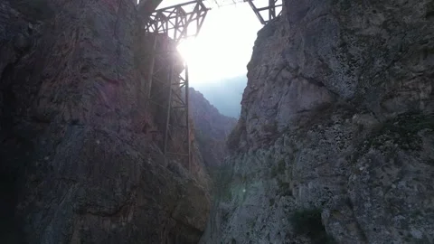 Rocky canyon features steel structure against steep cliffs under cloudy sky Stock Footage 342706034