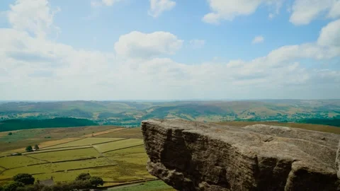 Rocky cliff above patchwork fields and rolling valley. Massive granite formation Stock Footage 346038136