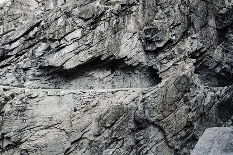 A rocky cliff with a small opening in it Stock Photos