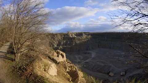A rocky cliff with sparse trees and dry bushes under warm sunlight. Stock Footage 303597836