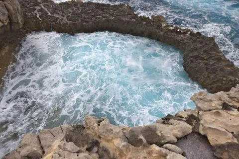 Rocky cliffs forming a pool with foaming blue water. Fotos de archivo