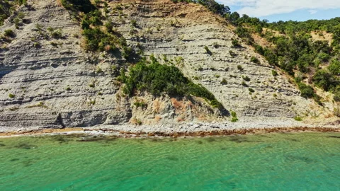 Rocky cliffs rise above clear water in a coastal area with natural formations Stock Footage 341112641