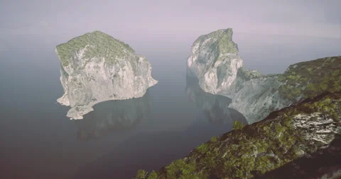Rocky cliffs rise from calm waters at daybreak near a quiet coastline Stock Footage 324713539