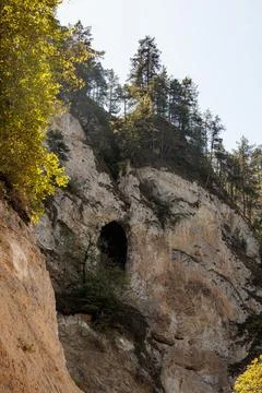Rocky cliffs with tree-covered slopes and natural caves. Bright sunlight Stock Photos