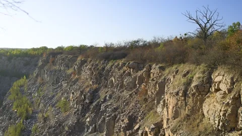 A rocky cliffside with sparse vegetation, including dry bushes Stock Footage 295149698